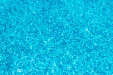 Background and rippled pattern texture of clear water in blue swimming pool.