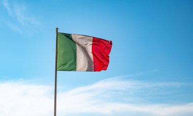 Mavi gökyüzü arka planında sallanan İtalyan Bayrağı.