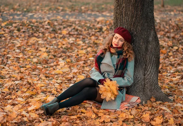 卷曲快乐的女孩 一双美丽的眼睛 穿着时髦的灰色外套 戴着格子围巾 坐在公园的一棵树旁 奥图姆时间 肖像画 — 图库照片