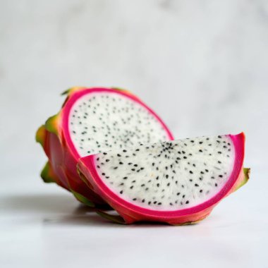 Dragon fruit slices cut halves styled in a basket on white background for enticing food displays clipart