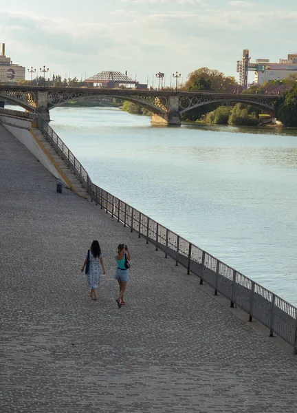 Две Туристки Прогуливаются Вдоль Реки Гвадалкивир Знаменитым Мостом Триана Заднем — стоковое фото
