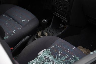 Ön yolcu koltuğunda kırık cam var. Araba camı taşla kırılmış. Sokağa park etmiş bir arabanın vandalizmi..