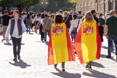 Seville, İspanya; 12 Kasım 2023: İspanya bayrağı taşıyan iki kadın merkez caddede yürüyor. İspanya bayrağını gösteren iki vatansever kadın.