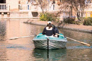 Seville, İspanya; 16 Kasım 2023: Sevilla Plaza de Espaa kanalında küçük bir sandalda kürek çeken kadın. Plaza de Espaa kanalında yelken açan turistler.