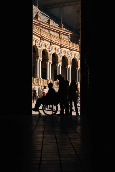 Seville, İspanya; 25 Ocak 2024: tekerlekli sandalye süren bir adamın silüeti. Arka planda Plaza de Espaa olan tekerlekli sandalyedeki bir adamın silueti..