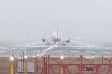 Ticari uçak sise iniyor. Sisli bir iniş sırasında uçak tekerlekleri piste değmek üzere..