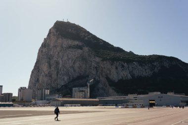 Cebelitarık, 26 Şubat 2024: Arka planda Kaya ile Cebelitarık Havalimanı 'nda yürüyen adam.