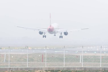 Seville, İspanya; 6 Şubat 2024: Sisli bir günde inmek üzere olan ticari bir uçağın arka görüntüsü.