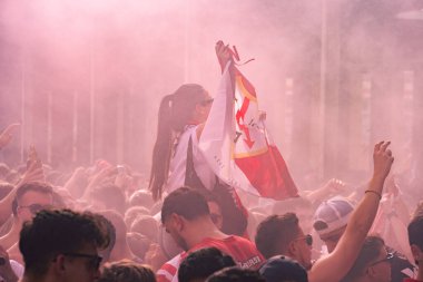 Seville, İspanya; 6 Ekim 2024: Bir erkeğin omuzlarında oturan bir kız, taraftarların maçtan önce takımlarına tezahürat yapmak için toplandıkları bir futbol bayrağı tutuyor.