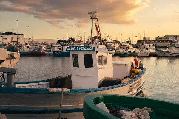 Santa Pola, İspanya; 27 Aralık 2024: Küçük balıkçı teknesi gün batımında limana yanaştı.