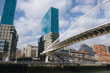 Bilbao, İspanya; 1 Mart 2025: Arka planda modern Isozaki Atea binaları bulunan ünlü Zubizuri Köprüsü 'nün altından bakın. Bilbao şehrinin modern kısmının manzarası.