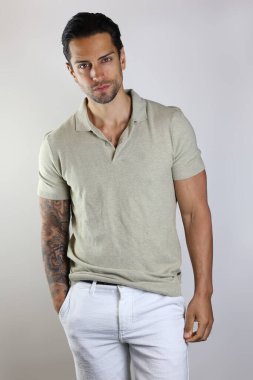 Gri arka planda izole edilmiş polo giyen yakışıklı bir kahverengi adamın resmi.