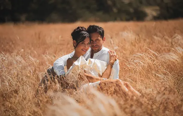一对迷人的已婚夫妇在日落时拥抱在一片金色的麦田里 完美的浪漫主题 图库照片