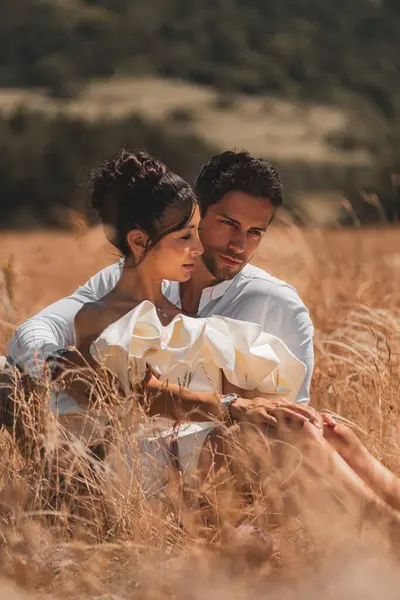見事な結婚したカップルは 日没の金の小麦畑のそばで抱擁しています 完璧なロマンチックなテーマ ストック写真