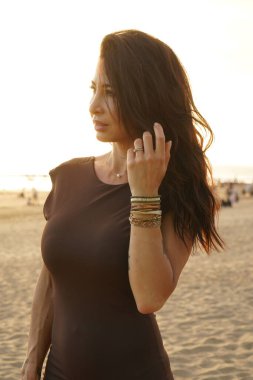 Yaz ışıltısı: Gün batımında kumsalda poz veren güzel esmer