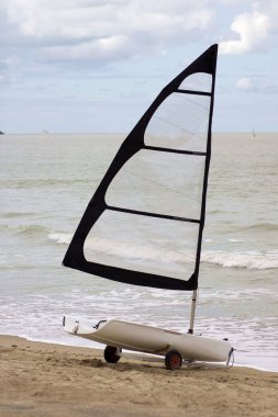 Yalnız yelkenli sabahın arka planında dalgalı deniz ve gökyüzünde