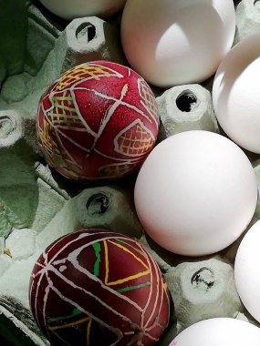 painted Easter eggs in Ukrainian style and a white egg in a tray clipart