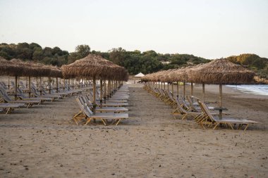 Şemsiyeler ve sahil sandalyeleri kumsalda otel yakınlarında Olympia Riviera Oteli - Kyllini, Moreloponnese, Yunanistan