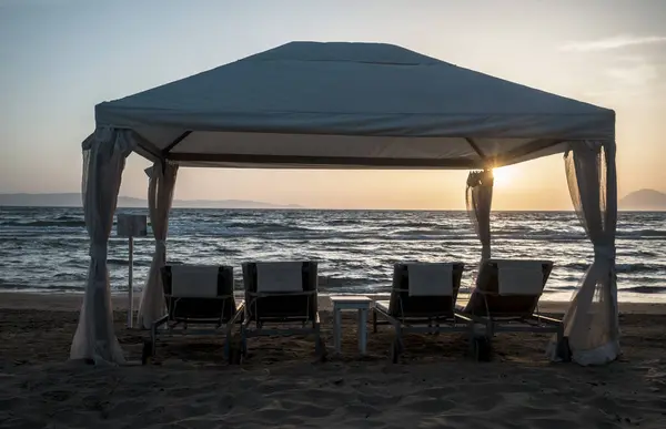 stock image Beach chair and white tent on a sandy beach at sunset