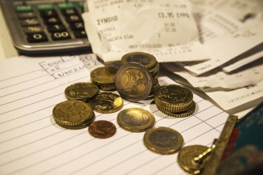 Budget - small coins, two euros, a calculator and receipts from a Greek supermarket clipart