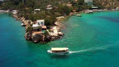 Türkiye 'nin Kas kentindeki Akdeniz kıyı şeridinde tek başına seyreden küçük bir turist teknesinin hava görüntüsü. Riviera tatil seyahati 