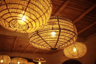 Hasır lambalar tavandan sarkıyor. İç mekanın doğal ve ekolojik el sanatları dekorasyonu..