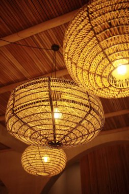 Hasır lambalar tavandan sarkıyor. İç mekanın doğal ve ekolojik el sanatları dekorasyonu..