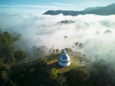 Beyaz bir Budist tapınağı Sri Lanka 'da bulutların ve ormanın üstündeki dağın tepesinde.