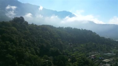 Bali tropikal doğasında bulutlarla çevrili yemyeşil dağlar ve tepeler.