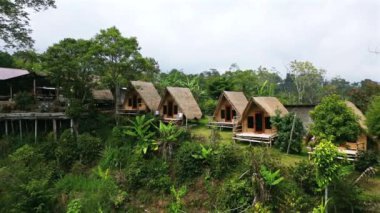 Bali dağlarında yuva yapmış, yemyeşil tropik otellerle çevrili bungalovların havadan görüntüsü.