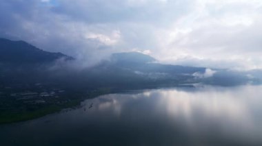 Bali 'deki Danau Buyan volkanik gölünün havadan görünüşü dağlar ve bulutlar arasında sakin bir manzara.
