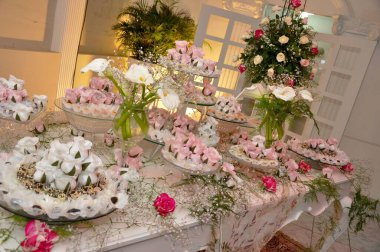 Lüks düğün tatlı masası pembe ve beyaz şekerlemelerle süslenmiş çok katmanlı cam tepsilerle süslenmiş, çiçeklerle süslenmiş güller ve 39 nolu bebeğin nefesi ile zenginleştirilmiş,.