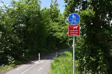 Selm, Almanya, 11 Haziran 2025 Bisiklet ve yaya yolu. Almanya 'da köpek tasması işareti var. Bir Alman bisikleti ve yaya yolu. Yol paylaşımına işaret eden tabelalar var.