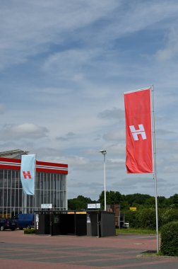 Selm, Almanya - 11 Haziran 2025: Selm 'de çağdaş bir binanın önünde belirgin bir şekilde kırmızı ve mavi bayraklar sergilenerek canlı bir şehir manzarası yaratıldı