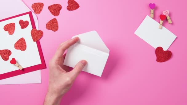 封筒ピンクの背景バラバラバレンタインデー祝日トップアングルトップビューモックアップ赤い心臓 — ストック動画