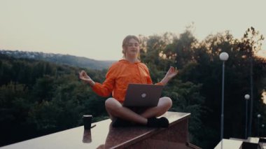 Yorgun genç öğrenci derslere ara veriyor, ellerini kaldırıyor, esniyor, sonra yüzünü odaya dönüyor ve gülümsüyor. Park şeridinde izole edilmiş. Parlak turuncu bir bluz giymişti, saçları da...