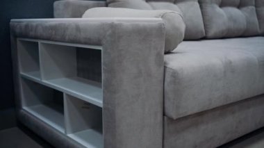 Gray sofa with decorative pillows. Sofa equipped with white side shelves. 4k video.
