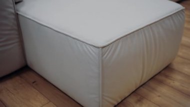 Slow shot to a piece of white sofa on a brown floor. 4k video