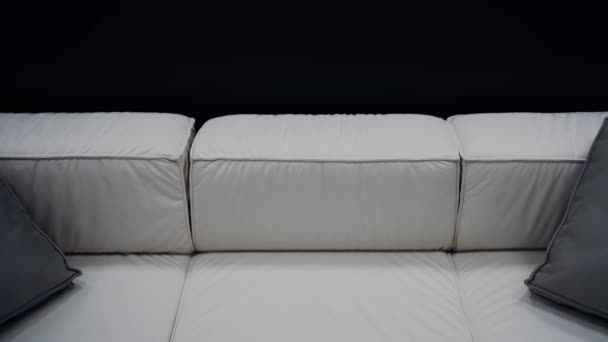 拍了一个舒适的白色沙发与两个灰色枕头在黑色背景 4K视频 — 图库视频影像