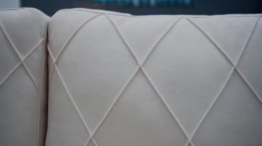 Eşkenar dörtgen şeklinde çizgileri olan beyaz kanepenin kalitesine yakın çekim. 4k video