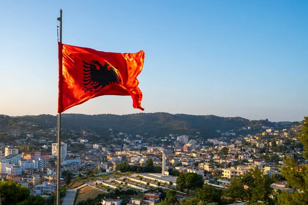 Albania flag. Albanian flag on a flagpole waving on a bright blue sky background.
