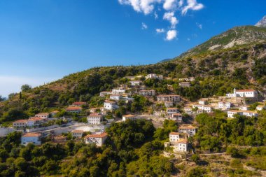 Sarı panjurlu, dağlı ve deniz manzaralı beyaz evler. Vuno, Arnavutluk.