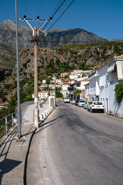 Sarı panjurlu, dağlı ve deniz manzaralı beyaz evler. Vuno, Arnavutluk.