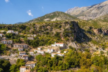 Sarı panjurlu, dağlı ve deniz manzaralı beyaz evler. Vuno, Arnavutluk