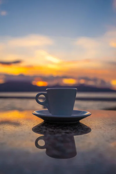 Cup of coffee on a table over blue sky and sea. Summer holiday concept.