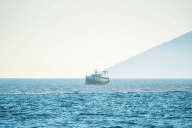 Denizde balıkçı teknesi ve balıkçı, denizin üstünde sisli bir sabah