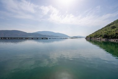 Güney Arnavutluk 'un Ksamil kentinde midye çiftliği ve dağlarıyla Butrint Gölü manzarası