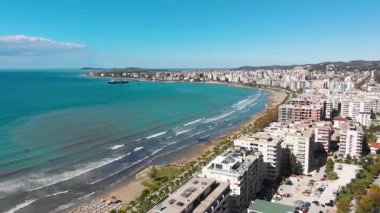Arnavutluk 'un Vlora kenti yakınlarındaki çarpıcı Riviera kıyı şeridinin insansız hava aracı görüntüsü, Saranda' da el değmemiş beyaz plajlar, turkuaz deniz suyu, kayalıklar ve Akdeniz güneşinin altındaki dağlar görülüyor.