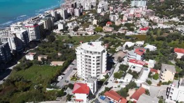 Arnavutluk 'un Vlora kenti yakınlarındaki çarpıcı Riviera kıyı şeridinin insansız hava aracı görüntüsü, Saranda' da el değmemiş beyaz plajlar, turkuaz deniz suyu, kayalıklar ve Akdeniz güneşinin altındaki dağlar görülüyor.