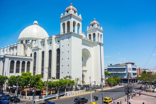 Вид на митрополита Сан-Сальвадора и Пласа-Риос в историческом центре сальвадорской столицы 15 марта 2013 года. Люди ходят и отдыхают на площади в солнечный день.